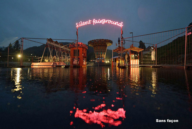 Night-time image of a carousel and fairground attractions reflected in a body of water